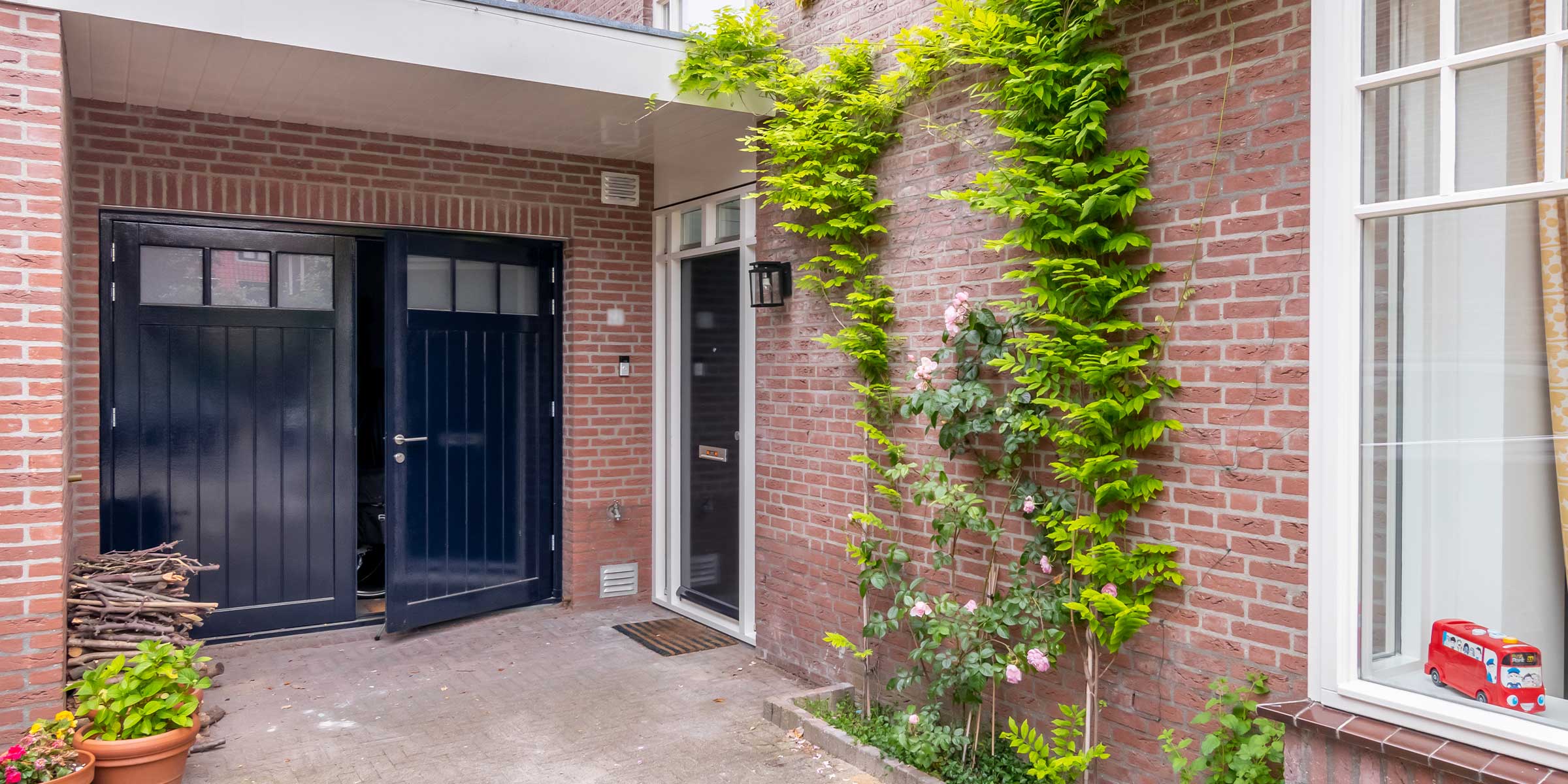 Blauwe houten openslaande garagedeur met glas